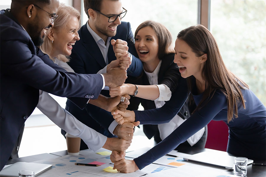 Contact - Group Of Excited Employees Stackign Their Hands Together On The Table In Office